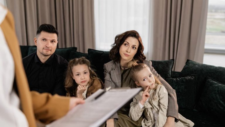 A family attentively listens during a consultation in a cozy living room setting.